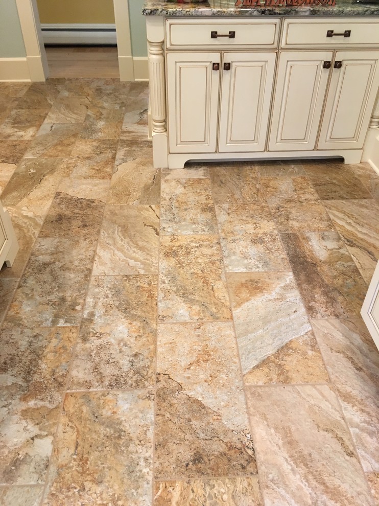Enclosed kitchen - large transitional galley porcelain tile enclosed kitchen idea with an undermount sink, raised-panel cabinets, distressed cabinets, granite countertops, beige backsplash, stone tile backsplash, stainless steel appliances and a peninsula