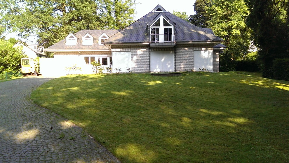 Große Landhaus Gartenmauer im Sommer mit direkter Sonneneinstrahlung und Natursteinplatten in Hamburg