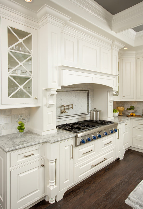 White traditional kitchen with raised-panel cabinets, brushed nickel pulls, marble counters, pot filler, and a stainless range—hardware shown is easy to clean