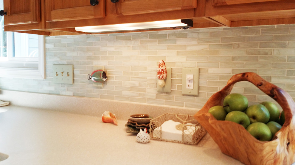Example of a mid-sized transitional u-shaped medium tone wood floor eat-in kitchen design with a farmhouse sink, raised-panel cabinets, light wood cabinets, soapstone countertops, beige backsplash, mosaic tile backsplash, stainless steel appliances and an island