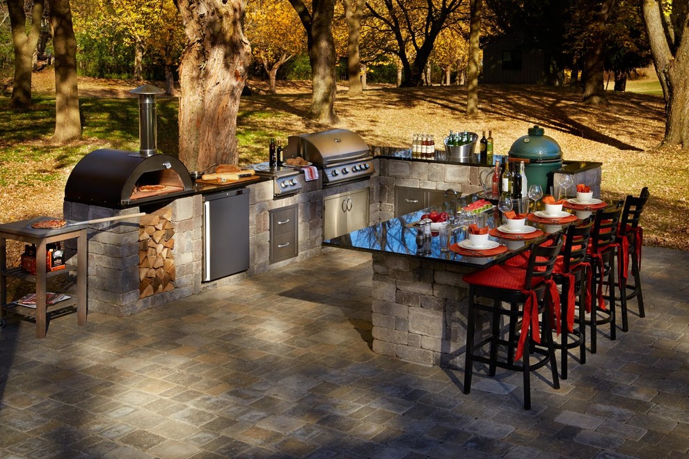 This is an example of a large transitional backyard patio in Minneapolis with an outdoor kitchen, brick pavers and no cover.