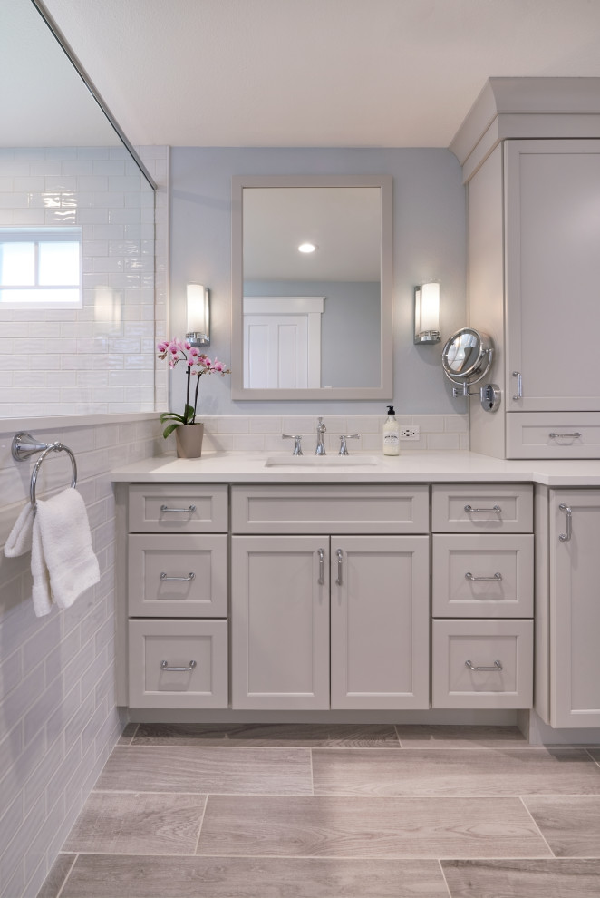 Inspiration for a mid-sized transitional master bathroom in Seattle with shaker cabinets, grey cabinets, a one-piece toilet, white tile, ceramic tile, blue walls, porcelain floors, an undermount sink, engineered quartz benchtops, a hinged shower door, white benchtops and grey floor.