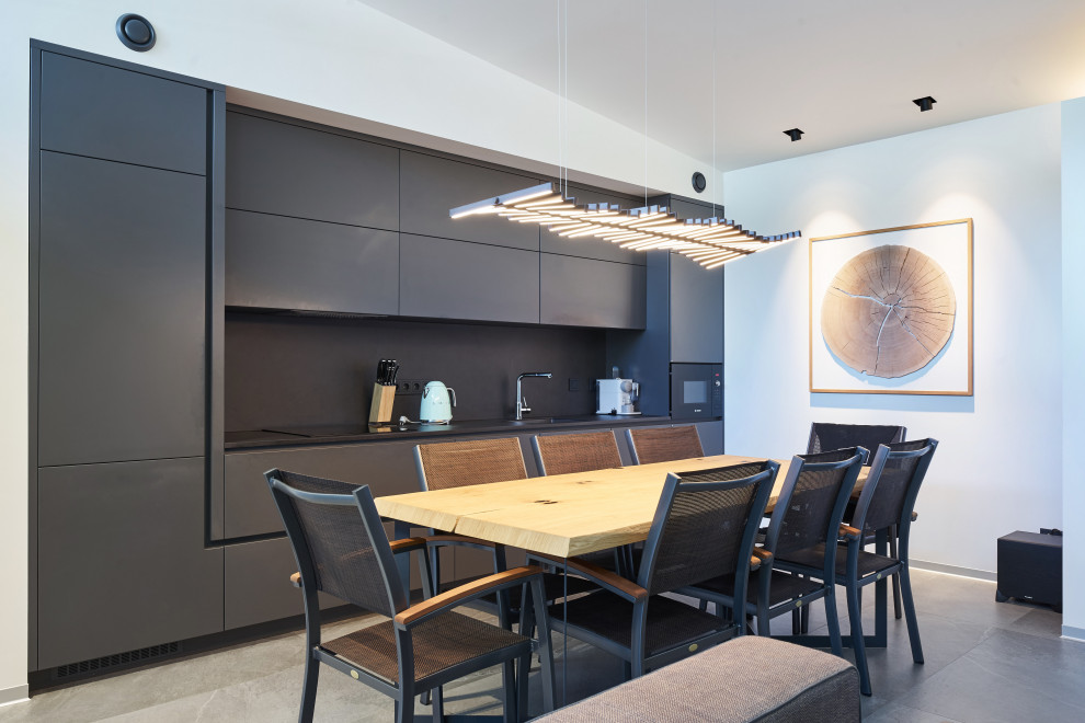 Inspiration for a mid-sized contemporary single-wall eat-in kitchen in Other with an integrated sink, flat-panel cabinets, black cabinets, black splashback, black appliances, porcelain floors, no island, grey floor and black benchtop.