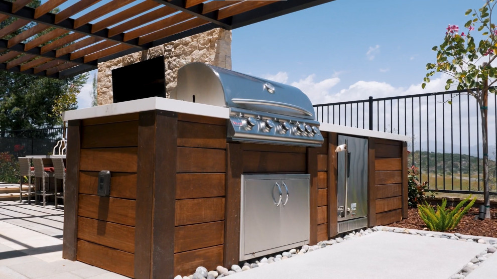 Aménagement d'une grande terrasse arrière moderne avec une cuisine d'été, du carrelage et une pergola.