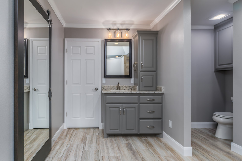 Example of a large transitional master porcelain tile porcelain tile and double-sink corner shower design with raised-panel cabinets, gray cabinets, a two-piece toilet, beige walls, an undermount sink, granite countertops and a built-in vanity