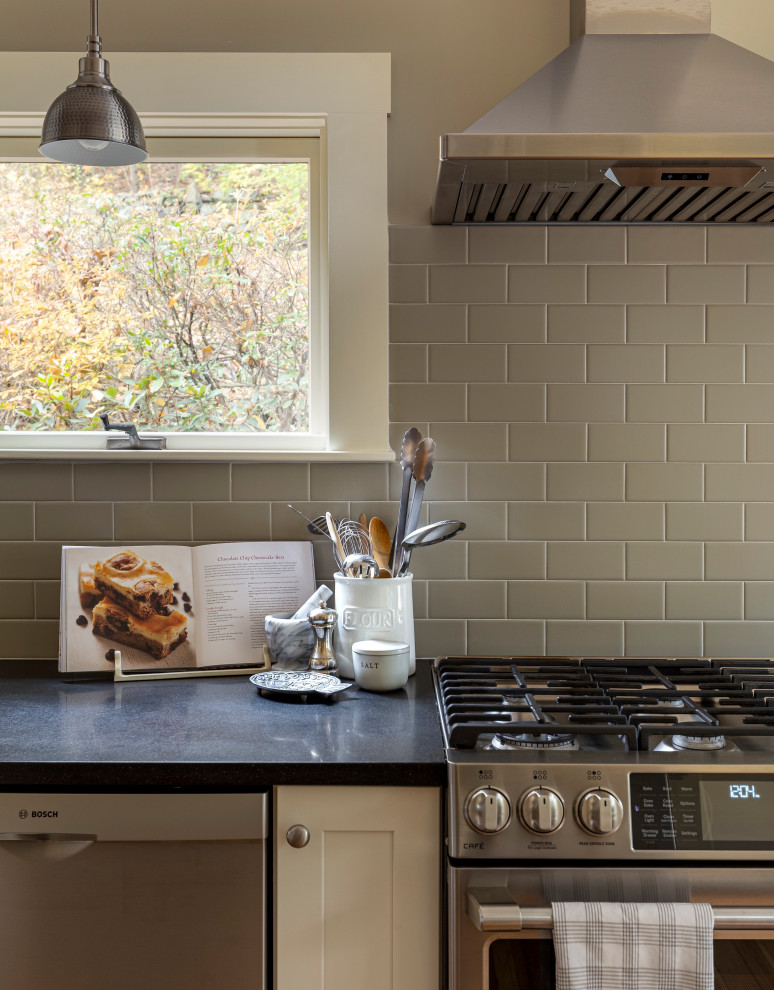 Example of a mid-sized transitional galley light wood floor kitchen pantry design in Boston with a farmhouse sink, shaker cabinets, white cabinets, granite countertops, gray backsplash, subway tile backsplash, stainless steel appliances, no island and black countertops