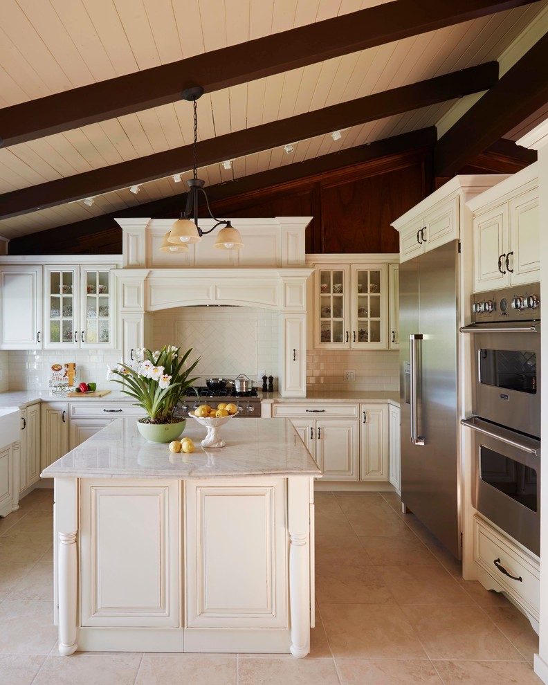 Inspiration for a large traditional u-shaped open plan kitchen in San Francisco with a farmhouse sink, raised-panel cabinets, beige cabinets, granite benchtops, white splashback, porcelain splashback, stainless steel appliances, travertine floors and with island.