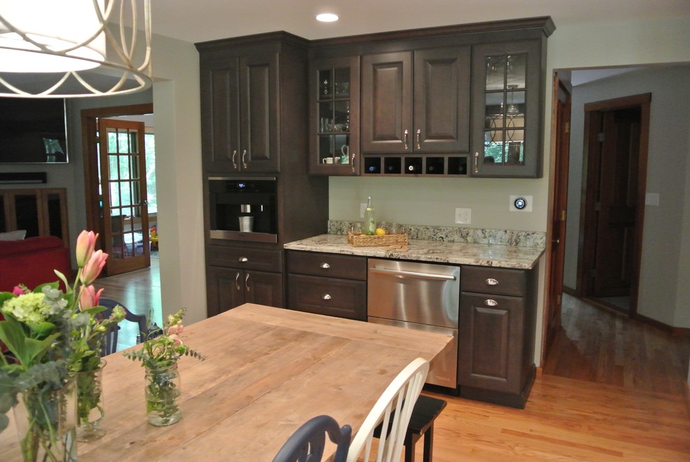 Eat-in kitchen - large transitional l-shaped light wood floor eat-in kitchen idea in Boston with a farmhouse sink, shaker cabinets, gray cabinets, granite countertops, white backsplash, ceramic backsplash, stainless steel appliances, an island and gray countertops
