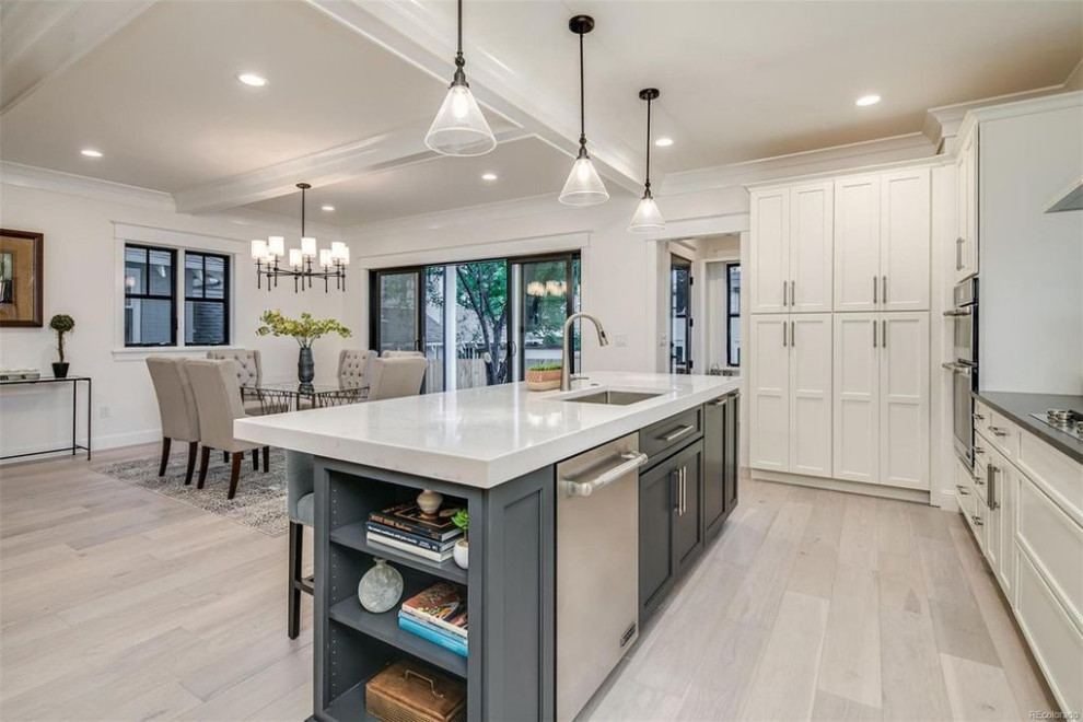 Inspiration for a mid-sized transitional l-shaped eat-in kitchen in Denver with an undermount sink, flat-panel cabinets, white cabinets, quartz benchtops, white splashback, ceramic splashback, stainless steel appliances, light hardwood floors, with island, grey floor, white benchtop and coffered.