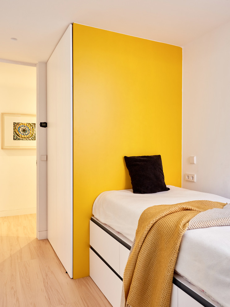 Large scandinavian gender-neutral kids' bedroom in Madrid with yellow walls, light hardwood floors and brown floor for kids 4-10 years old.
