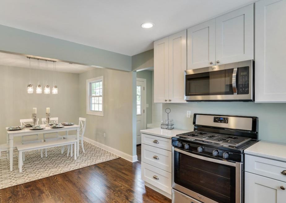 This is an example of a large transitional u-shaped eat-in kitchen in Philadelphia with an undermount sink, shaker cabinets, white cabinets, quartz benchtops, stainless steel appliances, medium hardwood floors, no island and white benchtop.