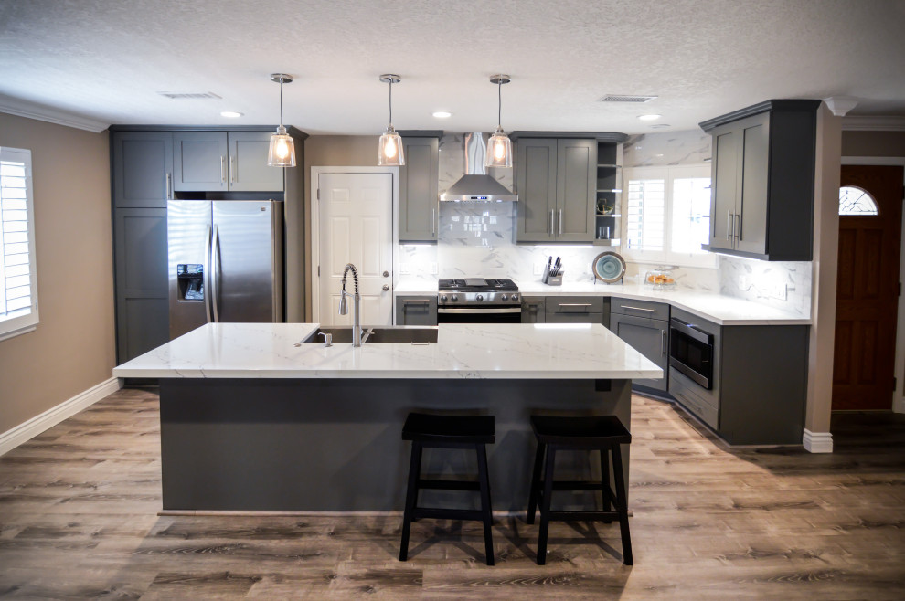 Inspiration for a large contemporary single-wall eat-in kitchen in Orange County with an undermount sink, shaker cabinets, grey cabinets, quartz benchtops, grey splashback, porcelain splashback, stainless steel appliances, light hardwood floors, with island and white benchtop.
