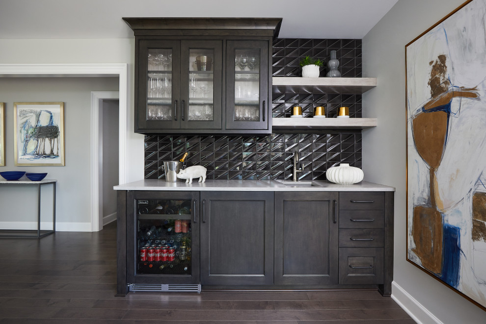 Mid-sized transitional single-wall dark wood floor and brown floor wet bar photo in Grand Rapids with an undermount sink, recessed-panel cabinets, black cabinets, quartz countertops, black backsplash, ceramic backsplash and white countertops