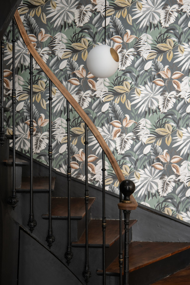 Large midcentury wood curved staircase in Saint-Etienne with painted wood risers, metal railing and wallpaper.
