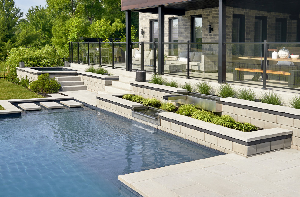 Design ideas for a modern backyard garden in Montreal with a retaining wall and concrete pavers.