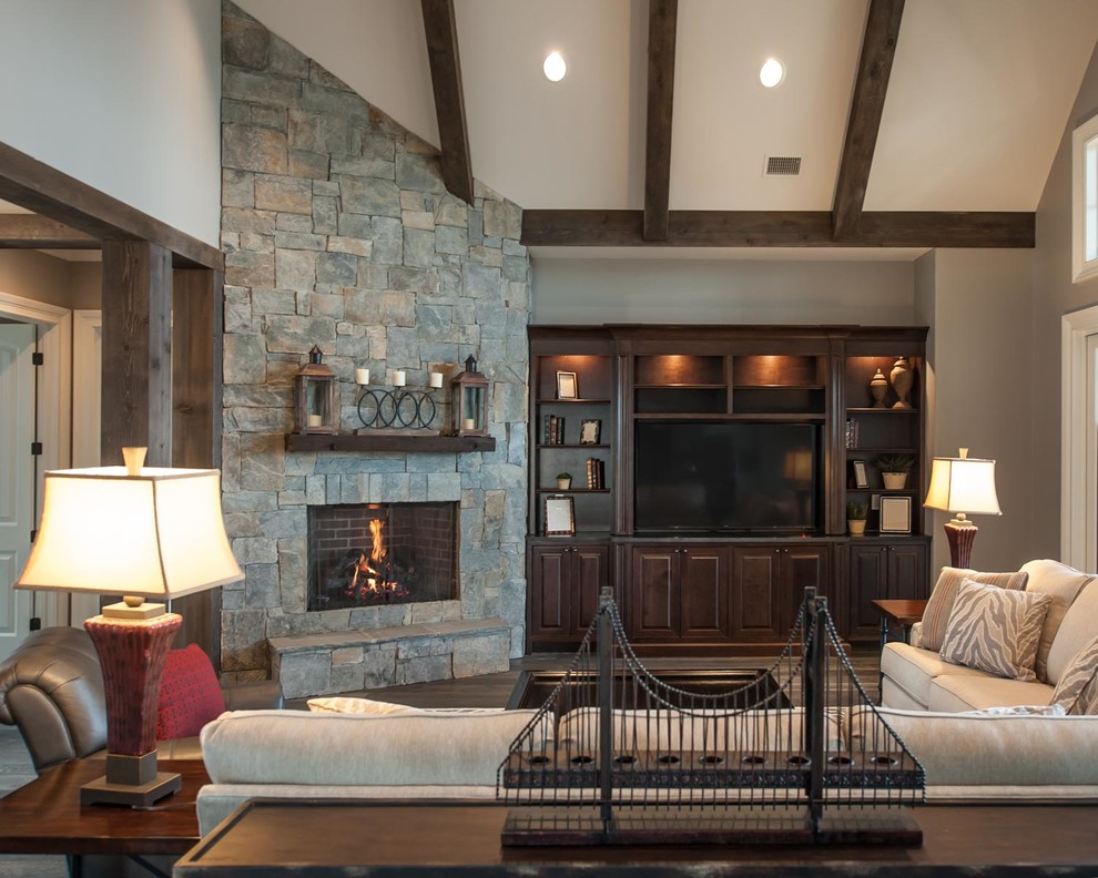 Photo of a mid-sized country formal open concept living room in Other with grey walls, dark hardwood floors, a corner fireplace, a stone fireplace surround and a built-in media wall.