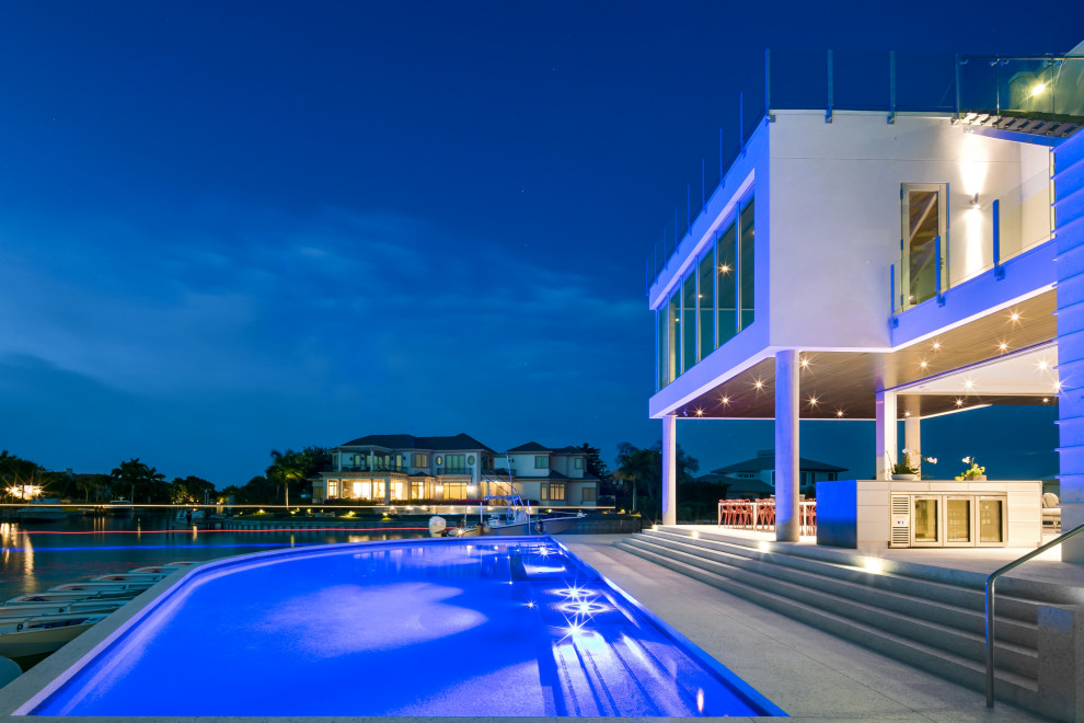 Large minimalist backyard concrete and custom-shaped aboveground pool photo in Tampa