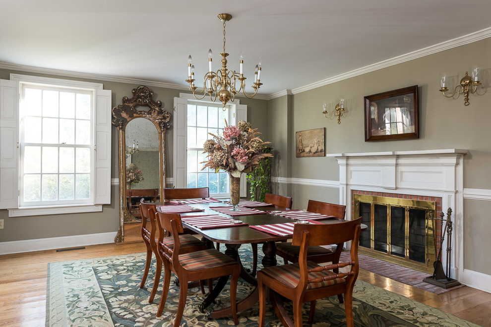 Design ideas for a mid-sized traditional separate dining room in Other with green walls, medium hardwood floors, a standard fireplace, a brick fireplace surround and brown floor.