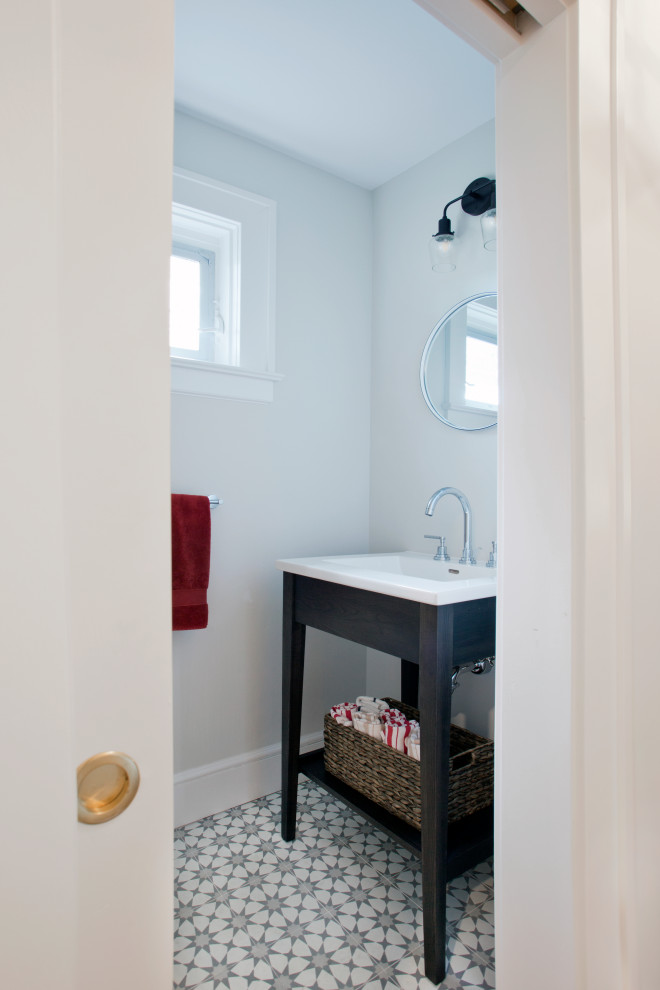 Small transitional powder room in New York with brown cabinets, a one-piece toilet, grey walls, cement tiles, an integrated sink, solid surface benchtops, multi-coloured floor, white benchtops and furniture-like cabinets.