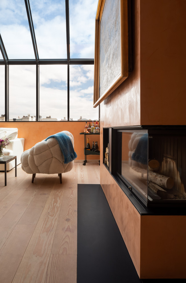 Imagen de salón minimalista de tamaño medio con parades naranjas, suelo de madera clara, chimenea de esquina y suelo marrón