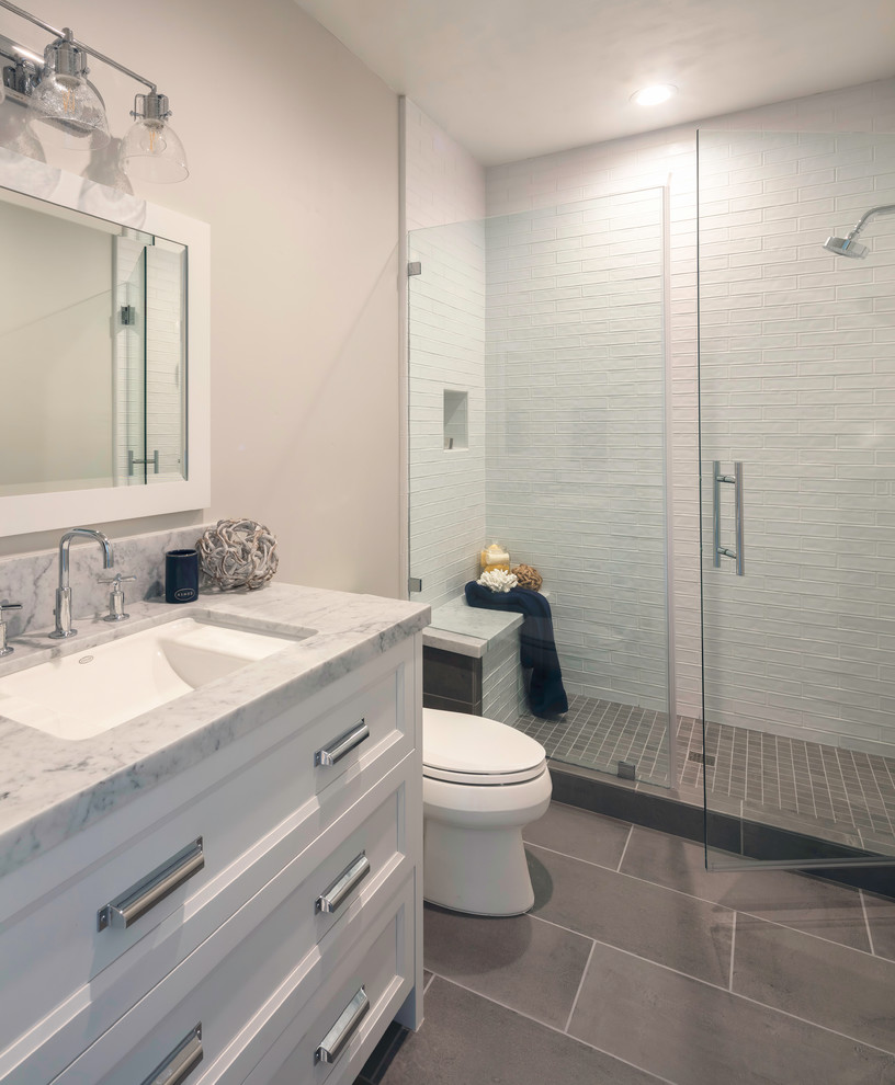 Photo of a mid-sized country 3/4 bathroom in San Francisco with shaker cabinets, white cabinets, a corner shower, a two-piece toilet, gray tile, ceramic tile, grey walls, ceramic floors, an undermount sink, marble benchtops, grey floor, a hinged shower door and grey benchtops.