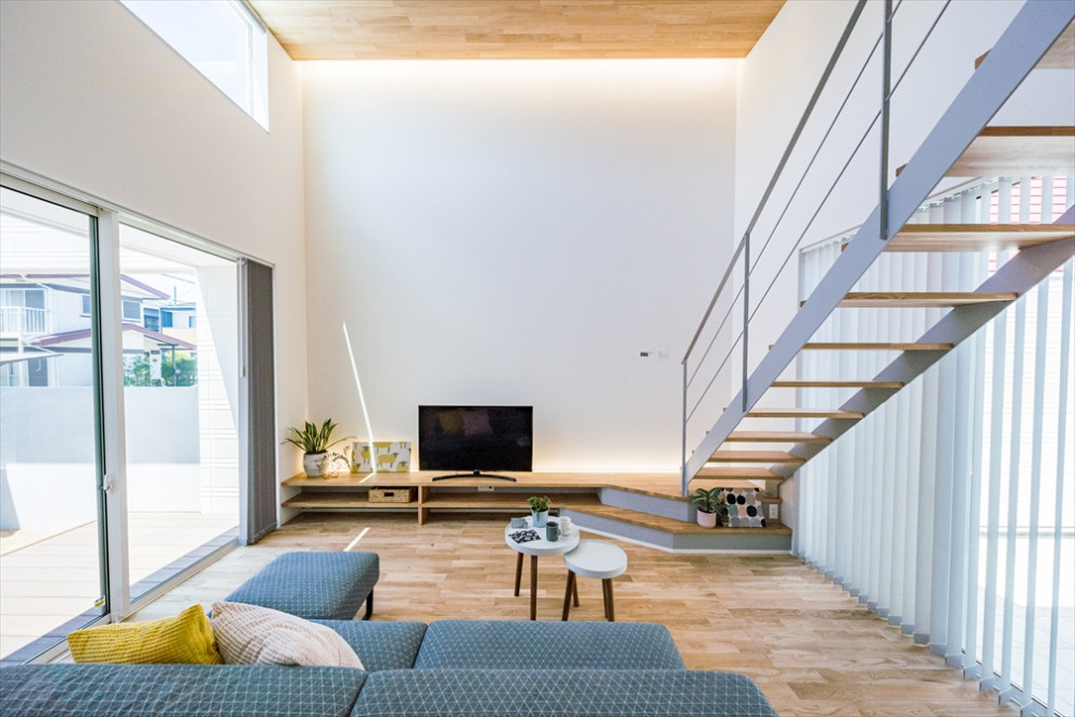 Diseño de salón para visitas abierto moderno con paredes blancas, suelo de madera en tonos medios, madera y papel pintado