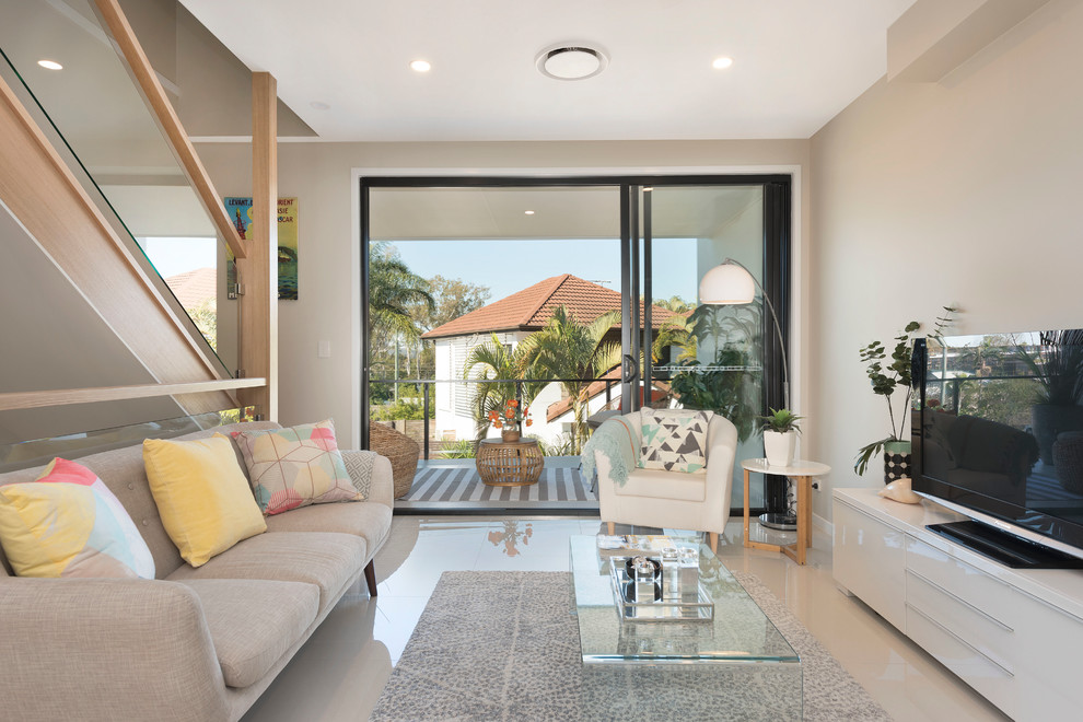 Small modern open concept living room in Brisbane with beige walls, porcelain floors, no fireplace, a freestanding tv and beige floor.