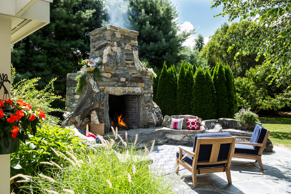 Inspiration for a large country backyard patio in New York with a fire feature, natural stone pavers and no cover.