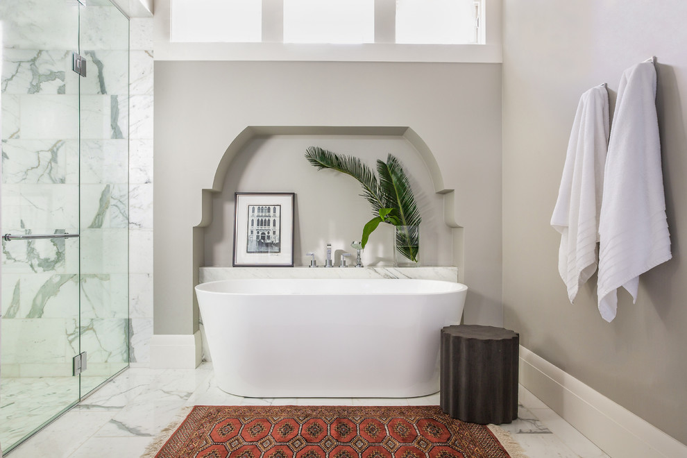 Design ideas for a mid-sized transitional master bathroom in Calgary with a freestanding tub, a corner shower, stone tile, beige walls, marble floors, a hinged shower door, marble benchtops and white floor.