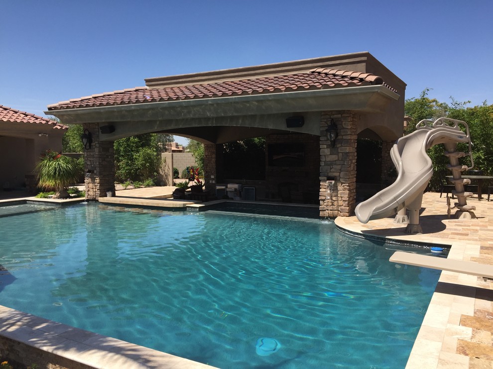 Large transitional backyard rectangular lap pool in Phoenix with a water slide and natural stone pavers.