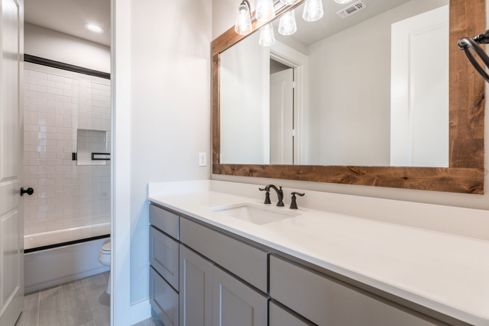 This is an example of a large country kids bathroom in Dallas with shaker cabinets, grey cabinets, a drop-in tub, a corner shower, white tile, subway tile, beige walls, porcelain floors, an undermount sink, engineered quartz benchtops, a shower curtain, white benchtops, a shower seat, a single vanity and a built-in vanity.
