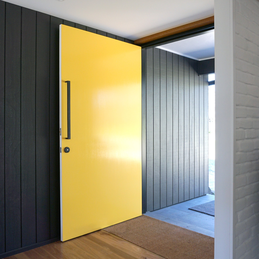 Photo of a mid-sized contemporary front door in Other with grey walls, medium hardwood floors, a single front door and a yellow front door.