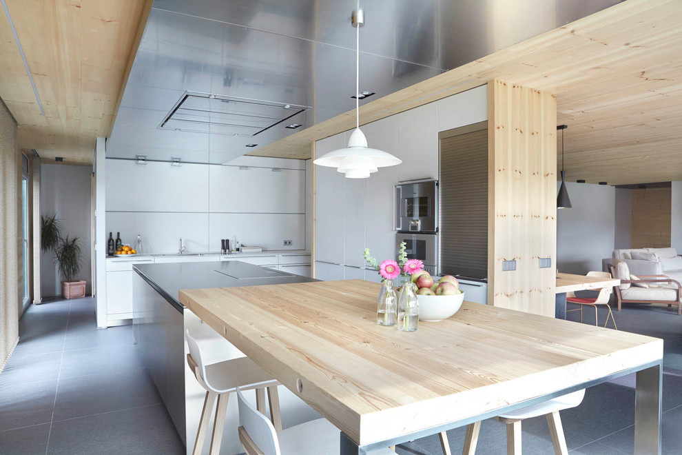 Photo of a large scandinavian u-shaped eat-in kitchen in Barcelona with flat-panel cabinets, white cabinets, white splashback, stainless steel appliances, concrete floors and multiple islands.