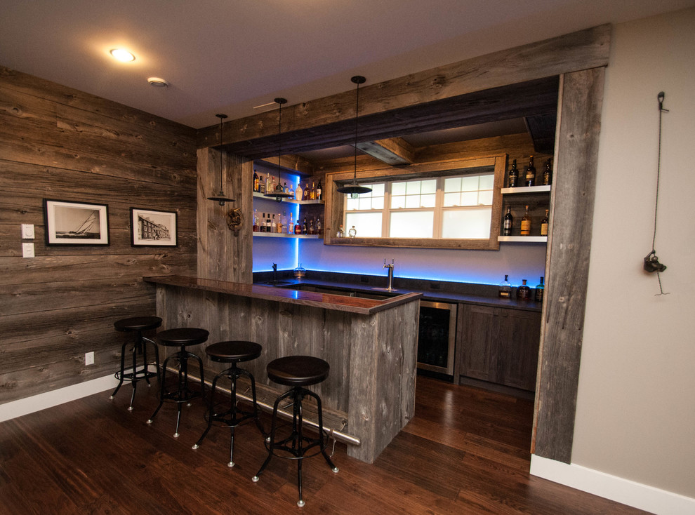 This is an example of a large country u-shaped seated home bar in Other with shaker cabinets, light wood cabinets, concrete benchtops, blue splashback, glass sheet splashback, dark hardwood floors and brown floor.