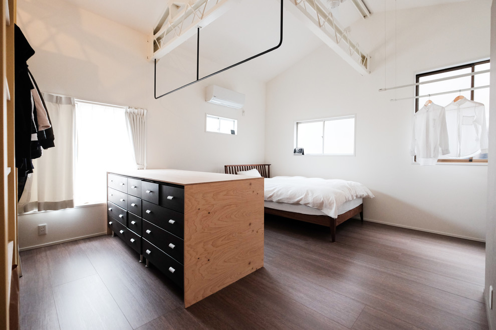 Immagine di una camera da letto industriale con pareti bianche, pavimento in legno verniciato e pavimento marrone