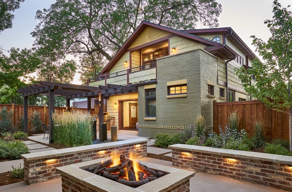 Large arts and crafts brick yellow house exterior in Denver with a gable roof and a shingle roof.