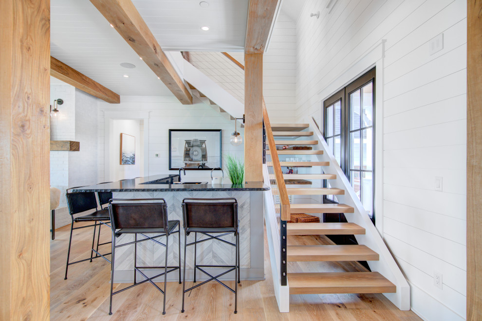 Diseño de escalera en L de estilo de casa de campo grande sin contrahuella con escalones de madera, barandilla de cable y machihembrado