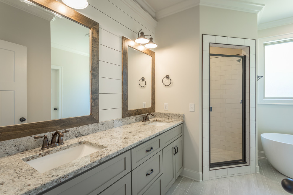 Inspiration for a large arts and crafts master bathroom in Other with shaker cabinets, grey cabinets, a freestanding tub, a corner shower, white tile, ceramic tile, grey walls, ceramic floors, an undermount sink, granite benchtops, beige floor and a hinged shower door.