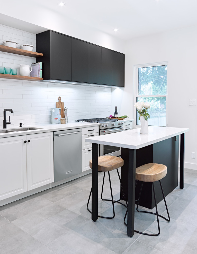 Photo of a mid-sized transitional galley separate kitchen in Toronto with an undermount sink, recessed-panel cabinets, black cabinets, quartz benchtops, white splashback, subway tile splashback, stainless steel appliances, porcelain floors, with island and grey floor.