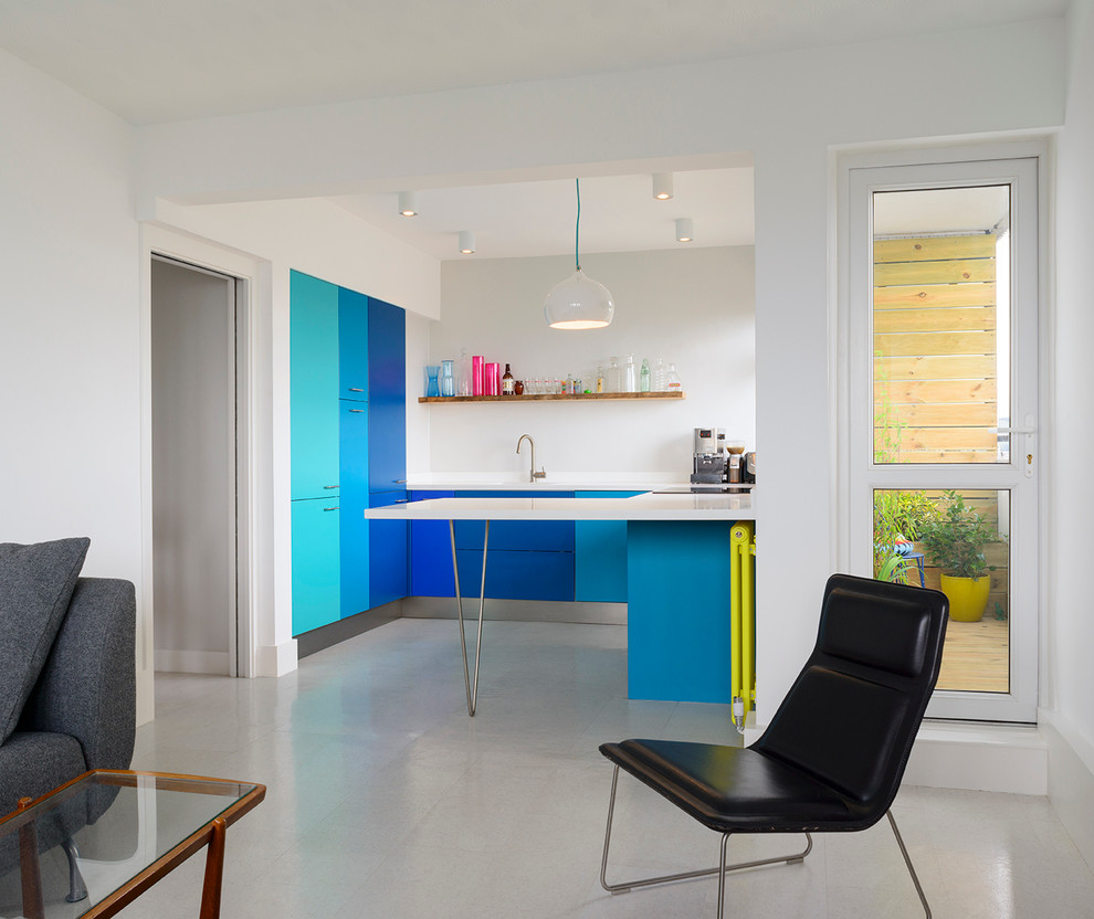 This is an example of a small contemporary u-shaped open plan kitchen in London with flat-panel cabinets, blue cabinets and a peninsula.