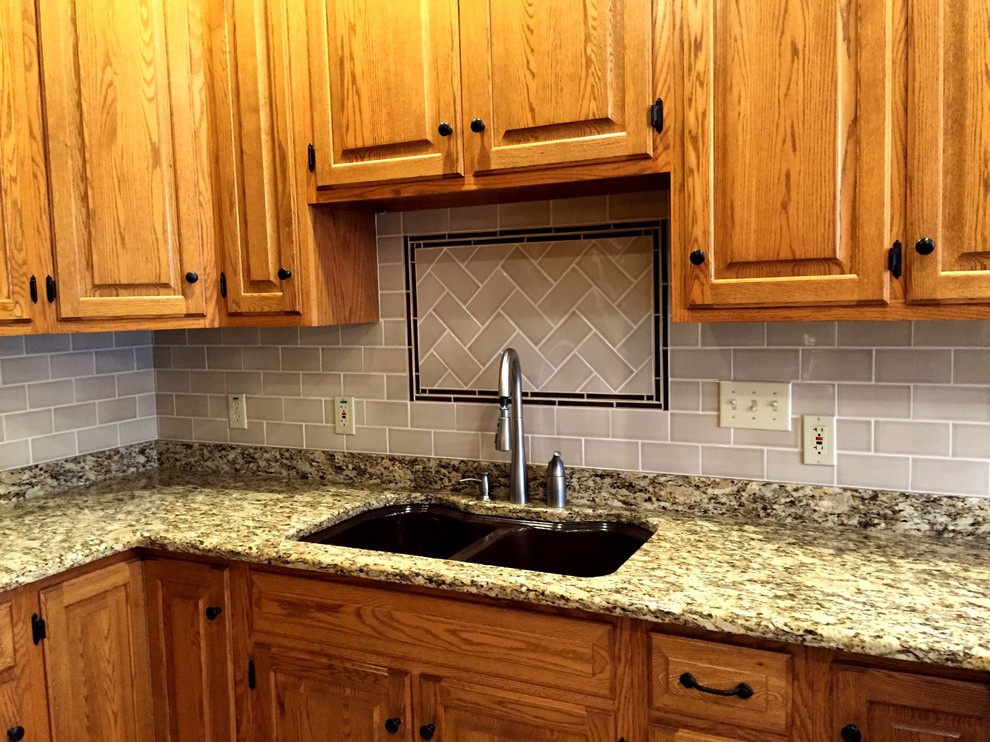 Eat-in kitchen photo in Milwaukee with a double-bowl sink, raised-panel cabinets, medium tone wood cabinets, gray backsplash, subway tile backsplash and stainless steel appliances