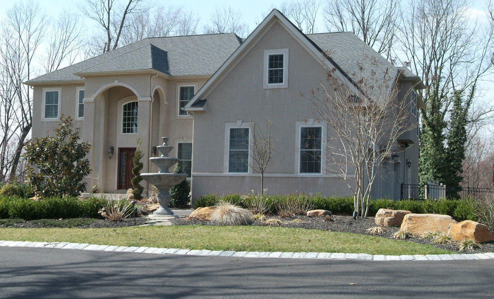 Photo of a large transitional two-storey stucco beige house exterior in Philadelphia with a gable roof and a shingle roof.