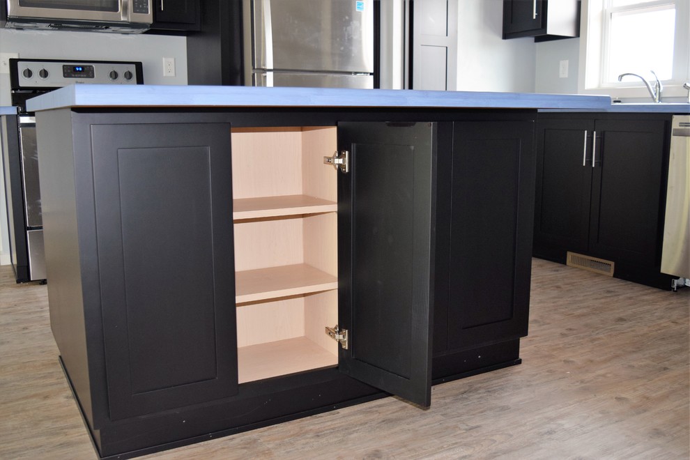 Inspiration for a l-shaped light wood floor open concept kitchen remodel with black cabinets, stainless steel appliances and an island