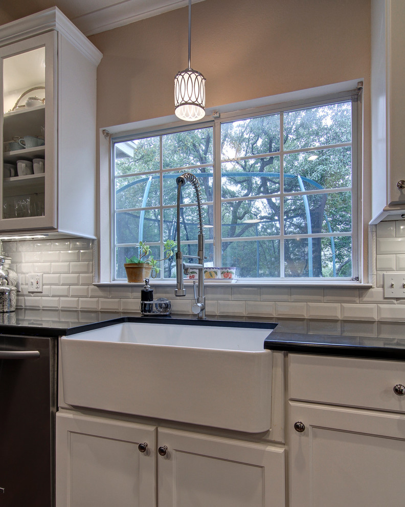 Photo of a transitional u-shaped eat-in kitchen in Austin with a farmhouse sink, recessed-panel cabinets, white cabinets, quartz benchtops, white splashback, subway tile splashback and stainless steel appliances.