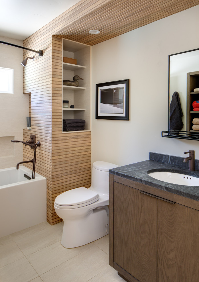 Mid-sized eclectic bathroom in San Diego with flat-panel cabinets, dark wood cabinets, an alcove tub, a one-piece toilet, white tile, porcelain tile, white walls, porcelain floors, an undermount sink, limestone benchtops, white floor, a shower curtain, black benchtops, a niche, a single vanity and a freestanding vanity.