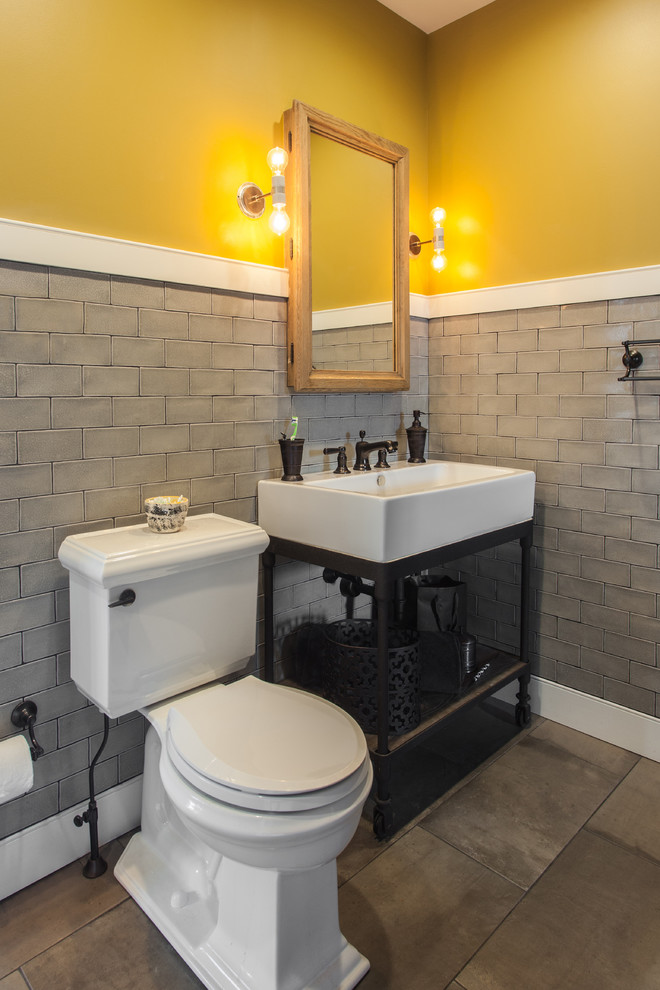 Photo of a mid-sized transitional kids bathroom in Philadelphia with open cabinets, distressed cabinets, an alcove tub, a shower/bathtub combo, a two-piece toilet, gray tile, ceramic tile, yellow walls, concrete floors, a console sink, zinc benchtops, grey floor and a shower curtain.