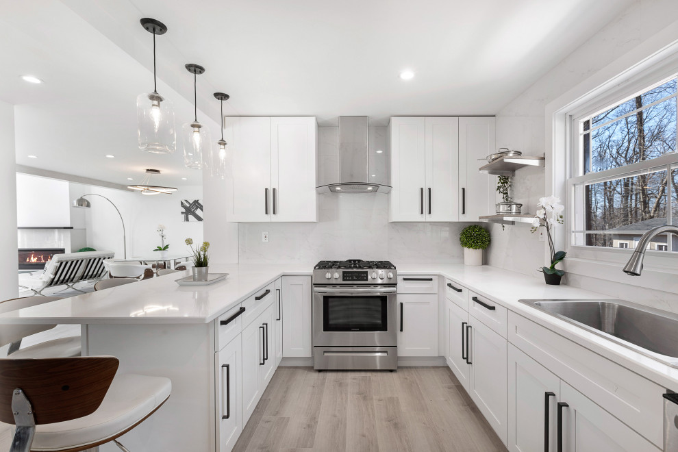 Modern Residential Construction - Eat-in kitchen - large modern l-shaped light wood floor, brown floor and coffered ceiling eat-in kitchen idea in Newark with a double-bowl sink, flat-panel cabinets, white cabinets, granite countertops, white backsplash, porcelain backsplash, stainless steel appliances, an island and white countertops