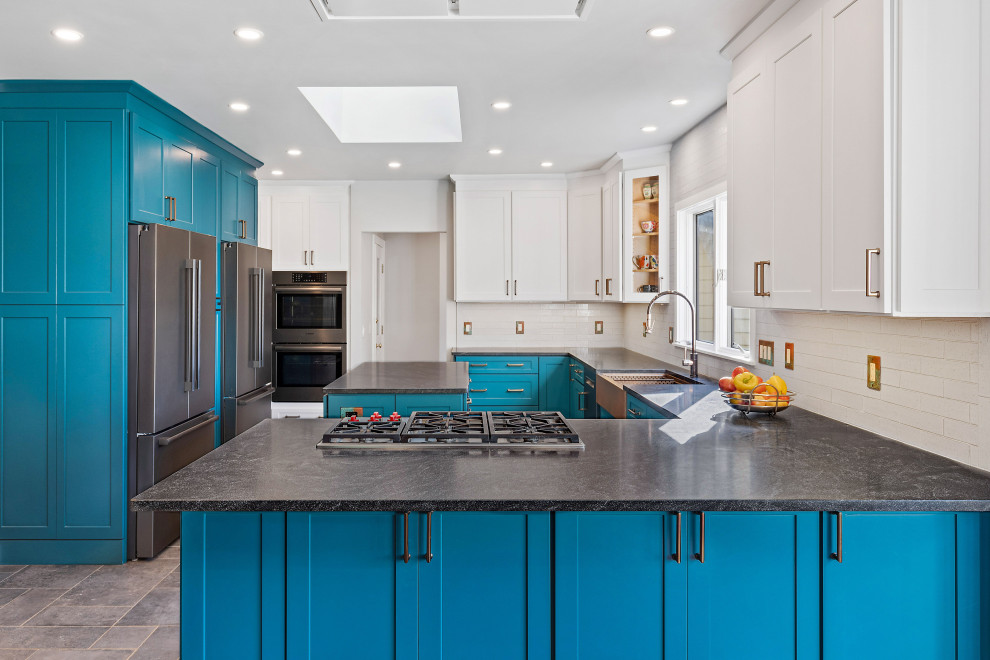 Example of a transitional porcelain tile kitchen design with a farmhouse sink, shaker cabinets, granite countertops, porcelain backsplash and black appliances
