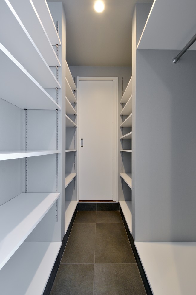 Пример оригинального дизайна: гардеробная комната унисекс в стиле модернизм с открытыми фасадами, белыми фасадами, полом из керамогранита и черным полом