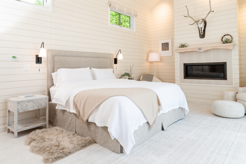 Large beach style master bedroom in Burlington with beige walls, light hardwood floors, a standard fireplace, white floor, timber and planked wall panelling.